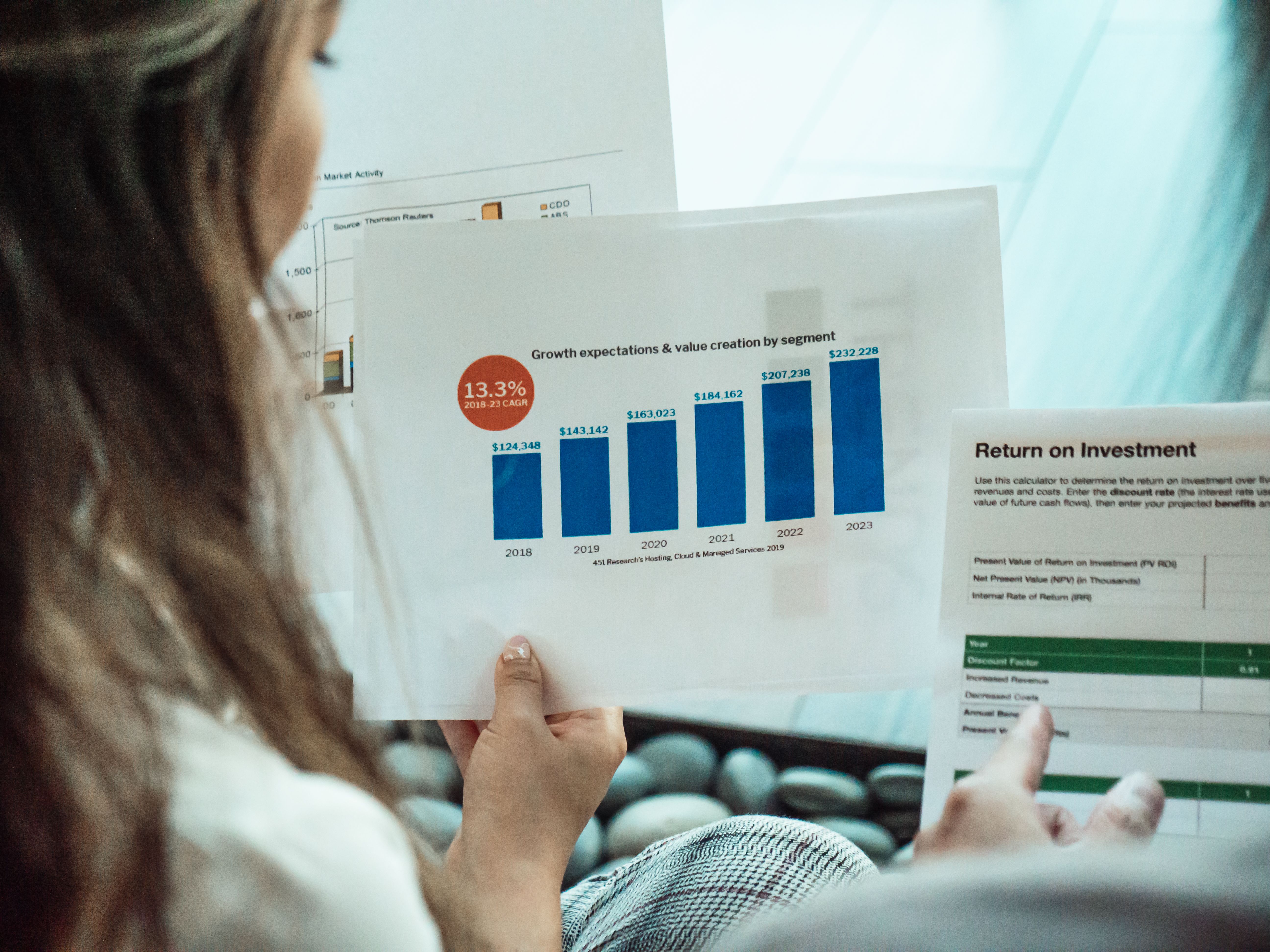 Person analyzing financial graphs and ROI reports focusing on bond and stock investment growth