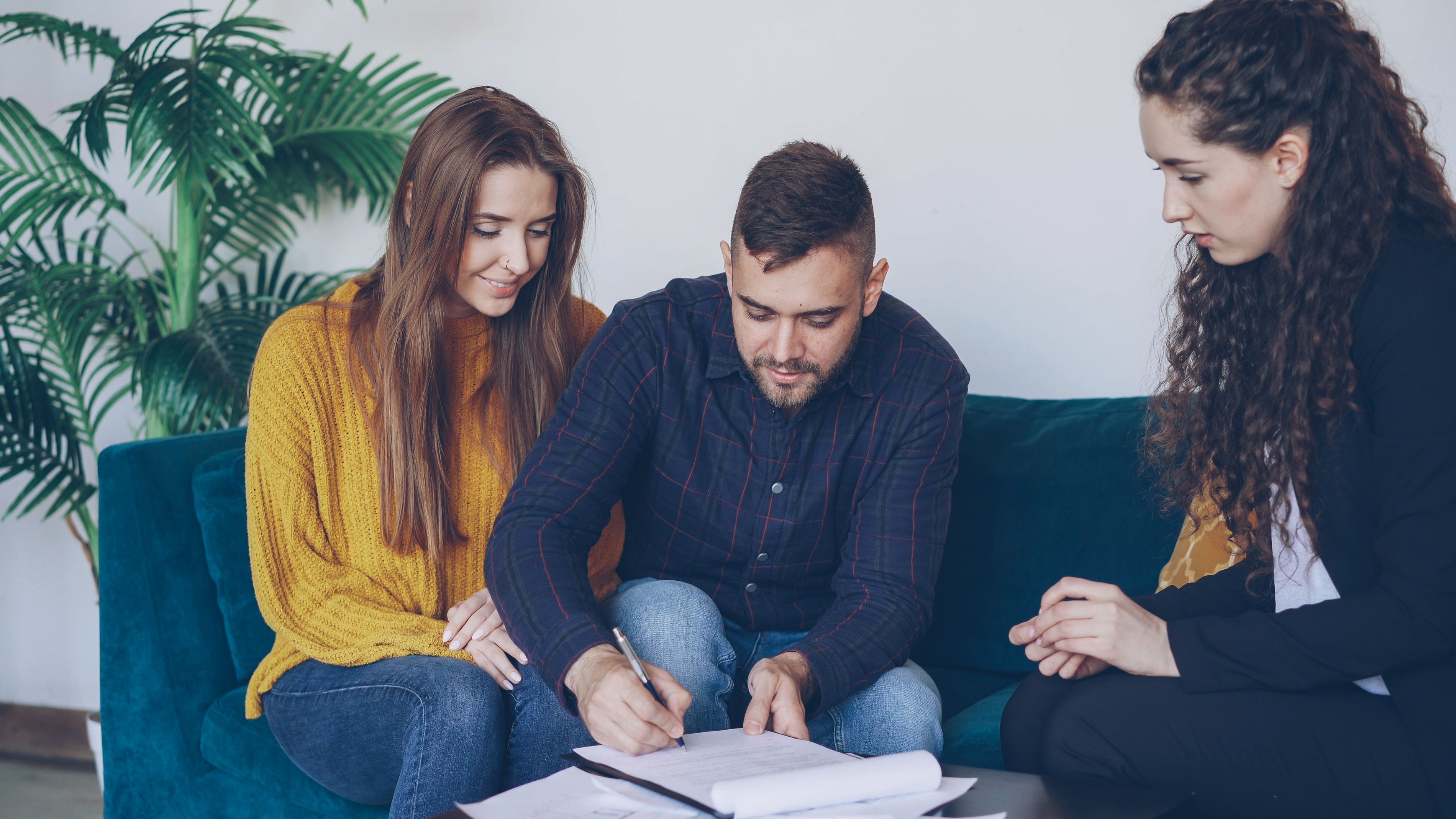 Young couple consulting a financial advisor and signing investment documents indoors