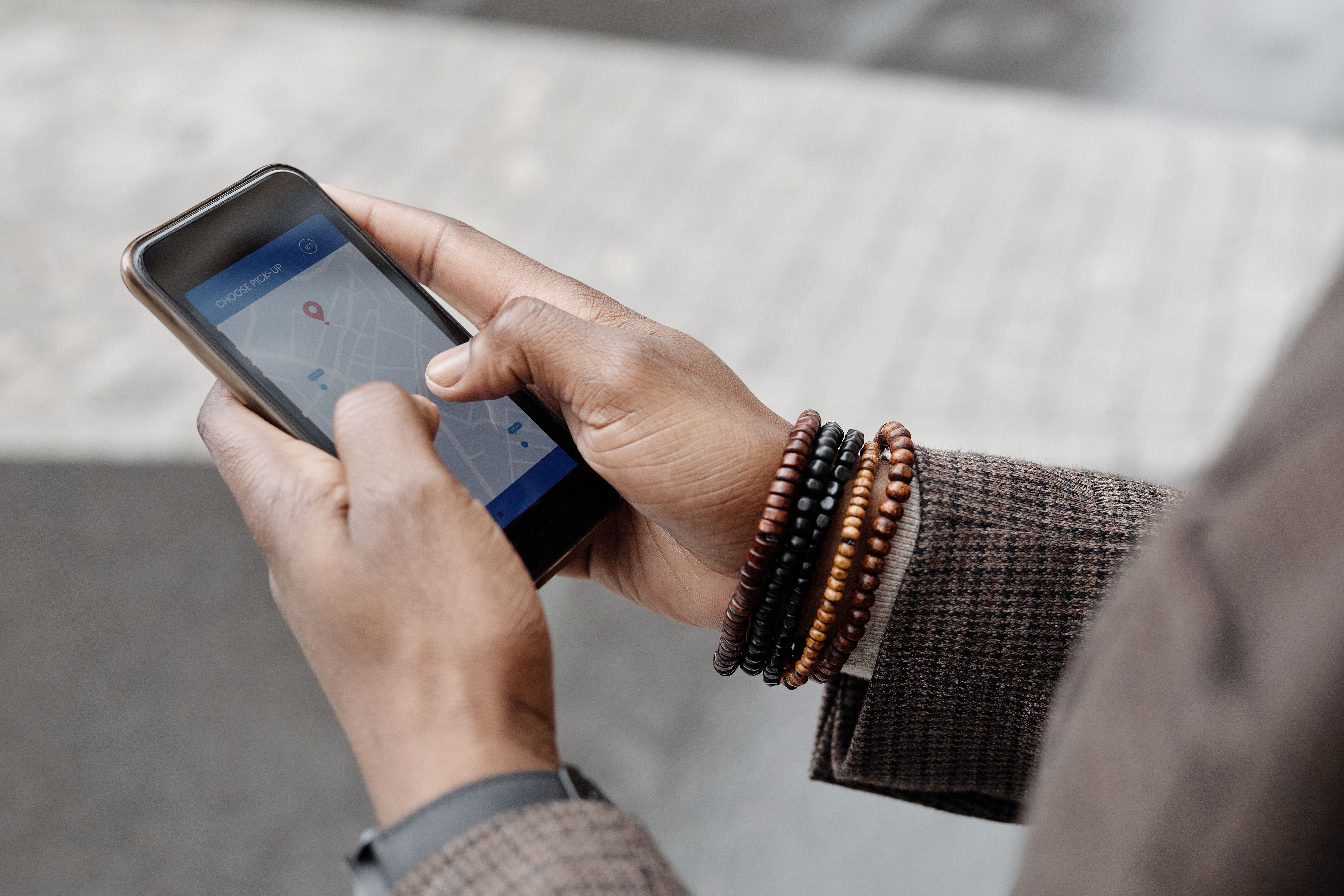 Hands navigating a GPS map app on a smartphone while searching for nearby local businesses