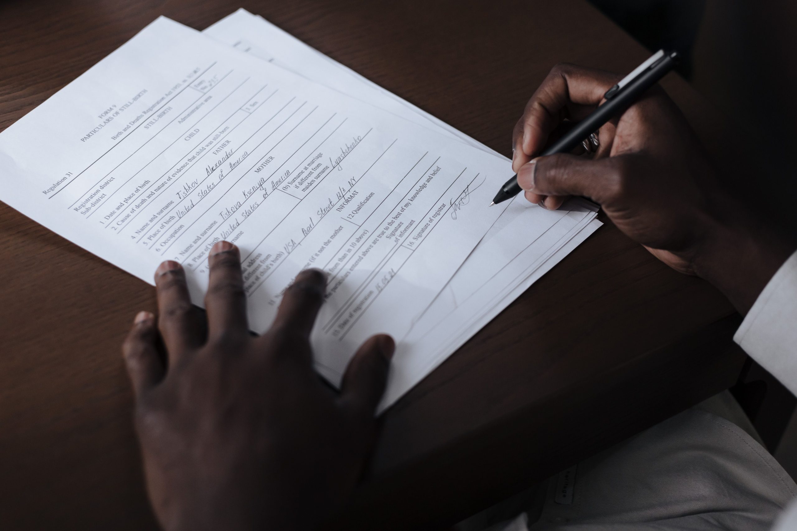 public-official-asset-declaration-signing Public official signing an asset declaration document with a pen at a desk