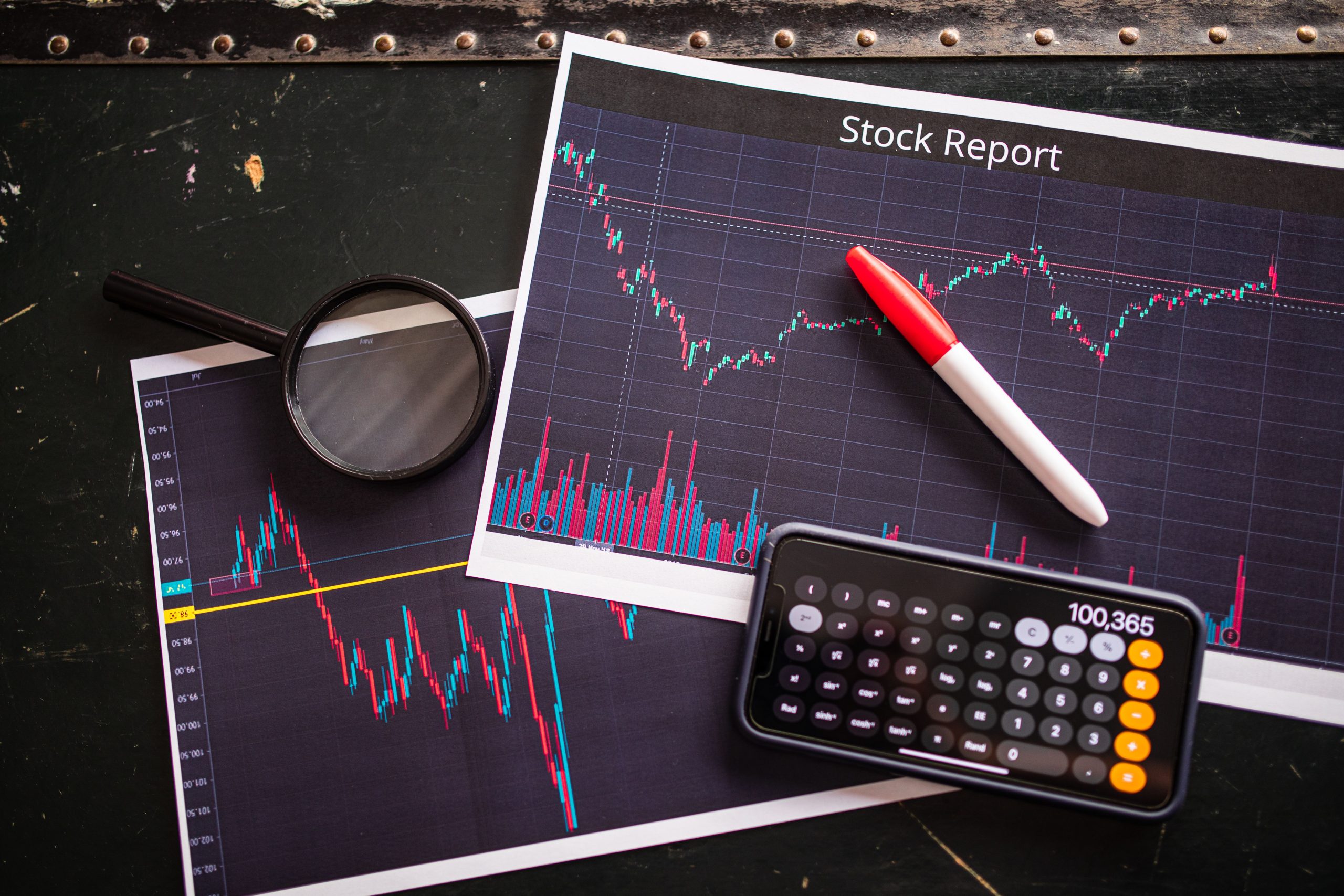 Top 10 Questions to Ask Before Investing in a Company\’s Stock or Bonds Stock report with charts, a calculator, and a magnifying glass used for financial analysis